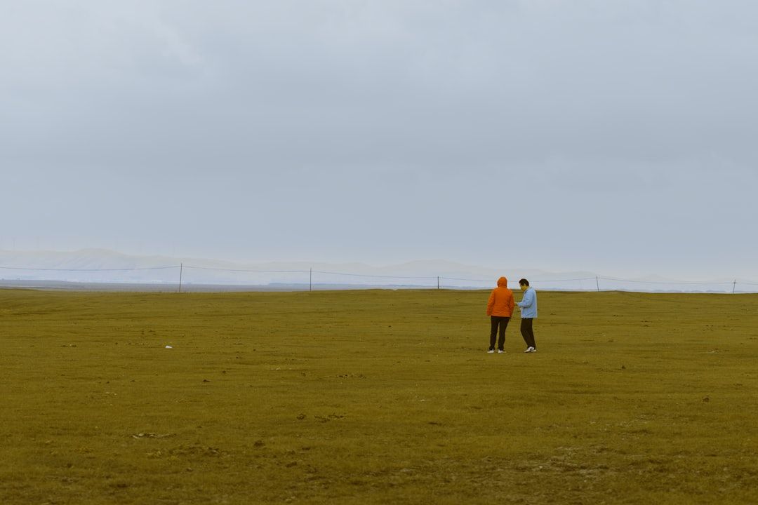 Två personer i fält med bergskedja i bakgrunden